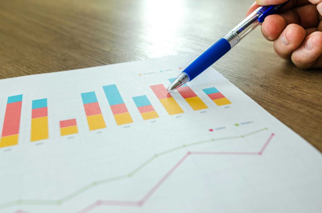 Graph on desk with hand holding a blue pen - link building and SEO strategies in Cornwall